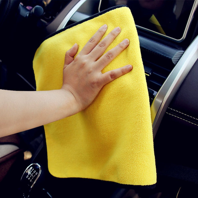 Person cleaning car interior with a yellow microfiber towel