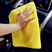 Person cleaning car interior with a yellow microfiber towel