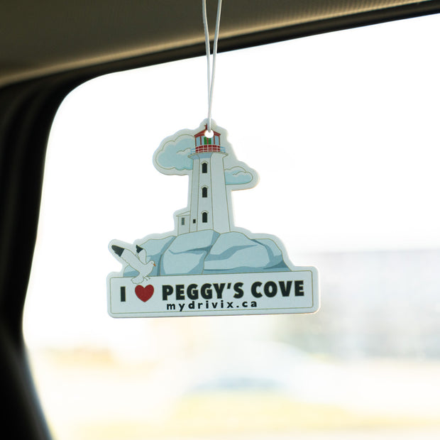Car air freshener with a lighthouse design hanging from a car's rearview mirror.