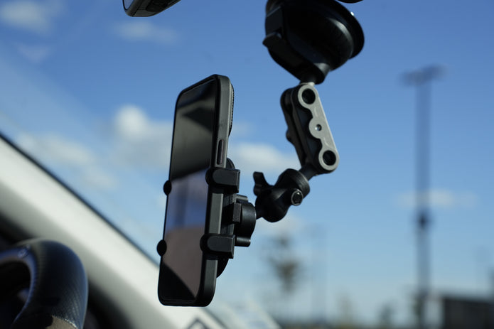 Phone mounted on a car dashboard with a clear blue sky background