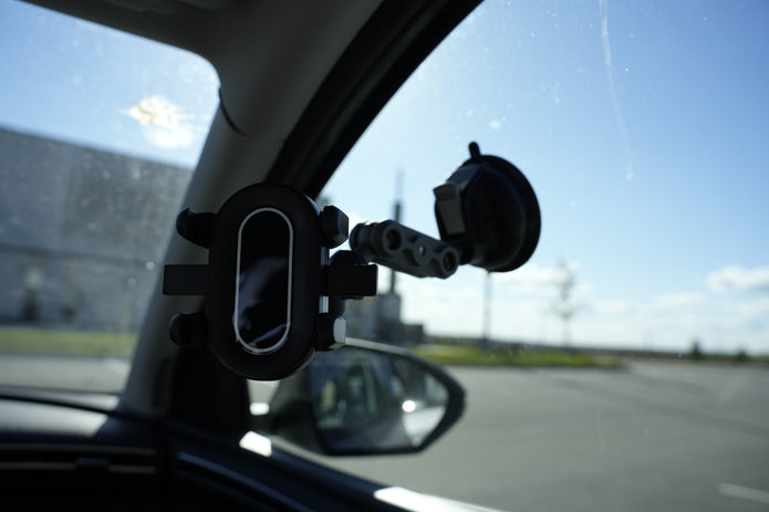 Car-mounted camera or sensor attached to a car's interior mirror with a clear sky background.