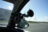Car-mounted camera or sensor attached to a car's interior mirror with a clear sky background.