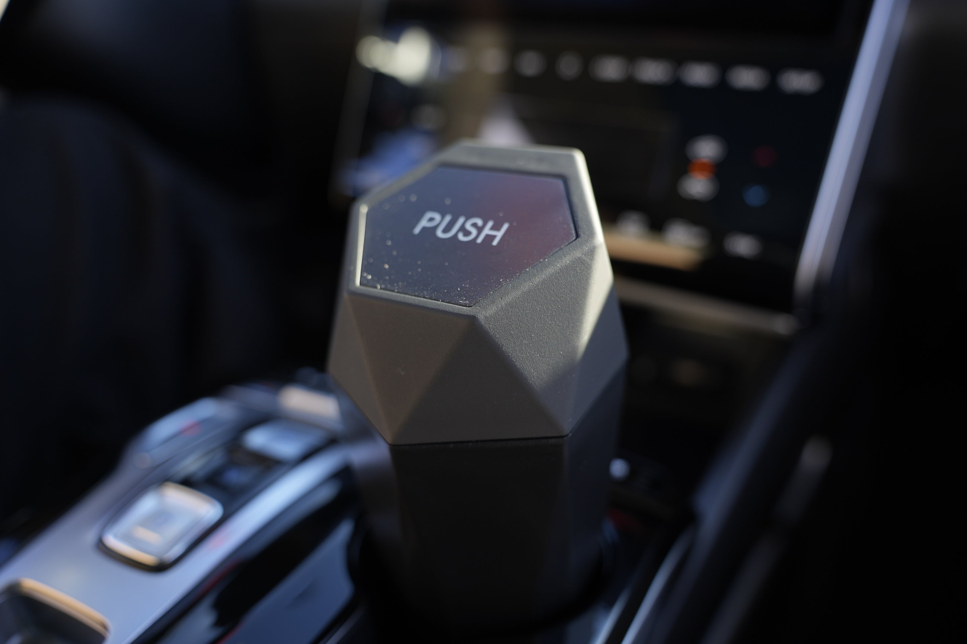 Hexagonal car air freshener with 'PUSH' label on a car dashboard