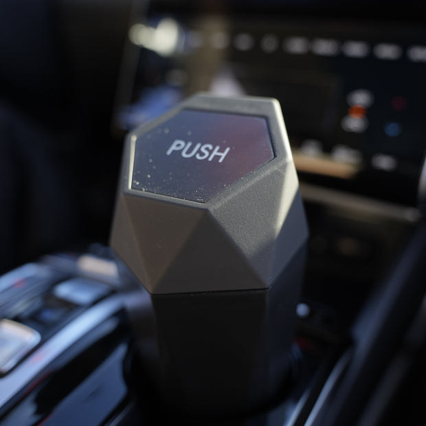 Hexagonal car air freshener with 'PUSH' label on a car dashboard
