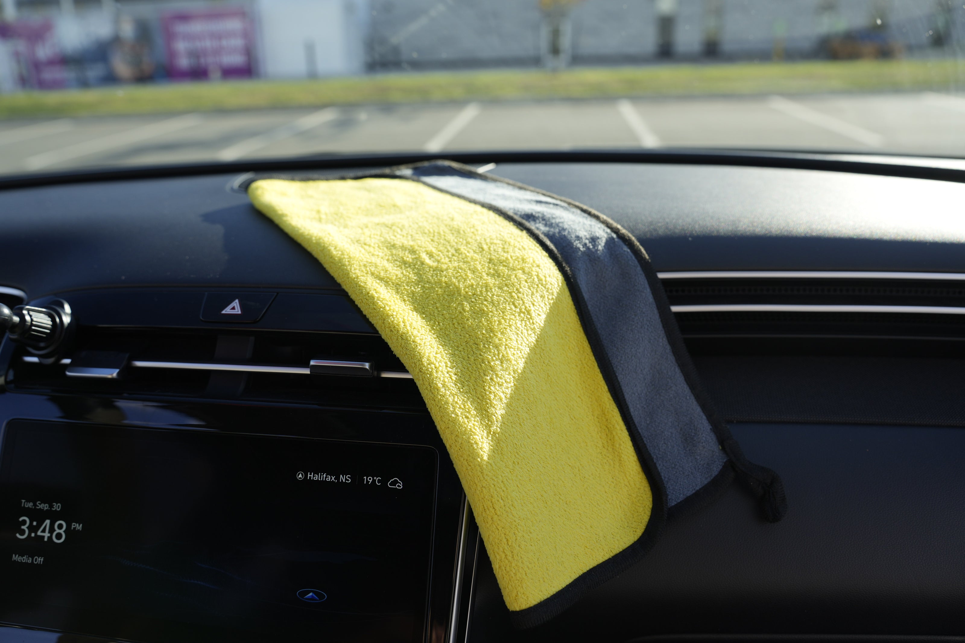 Yellow microfiber towel draped over a car's dashboard with a blurred background