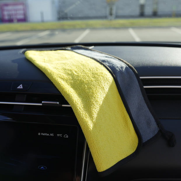 Yellow microfiber towel draped over a car's dashboard with a blurred background