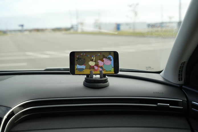 Phone mounted on a car dashboard displaying an app with cartoon characters.