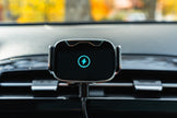 Wireless car charger on a car dashboard with a blurred outdoor background