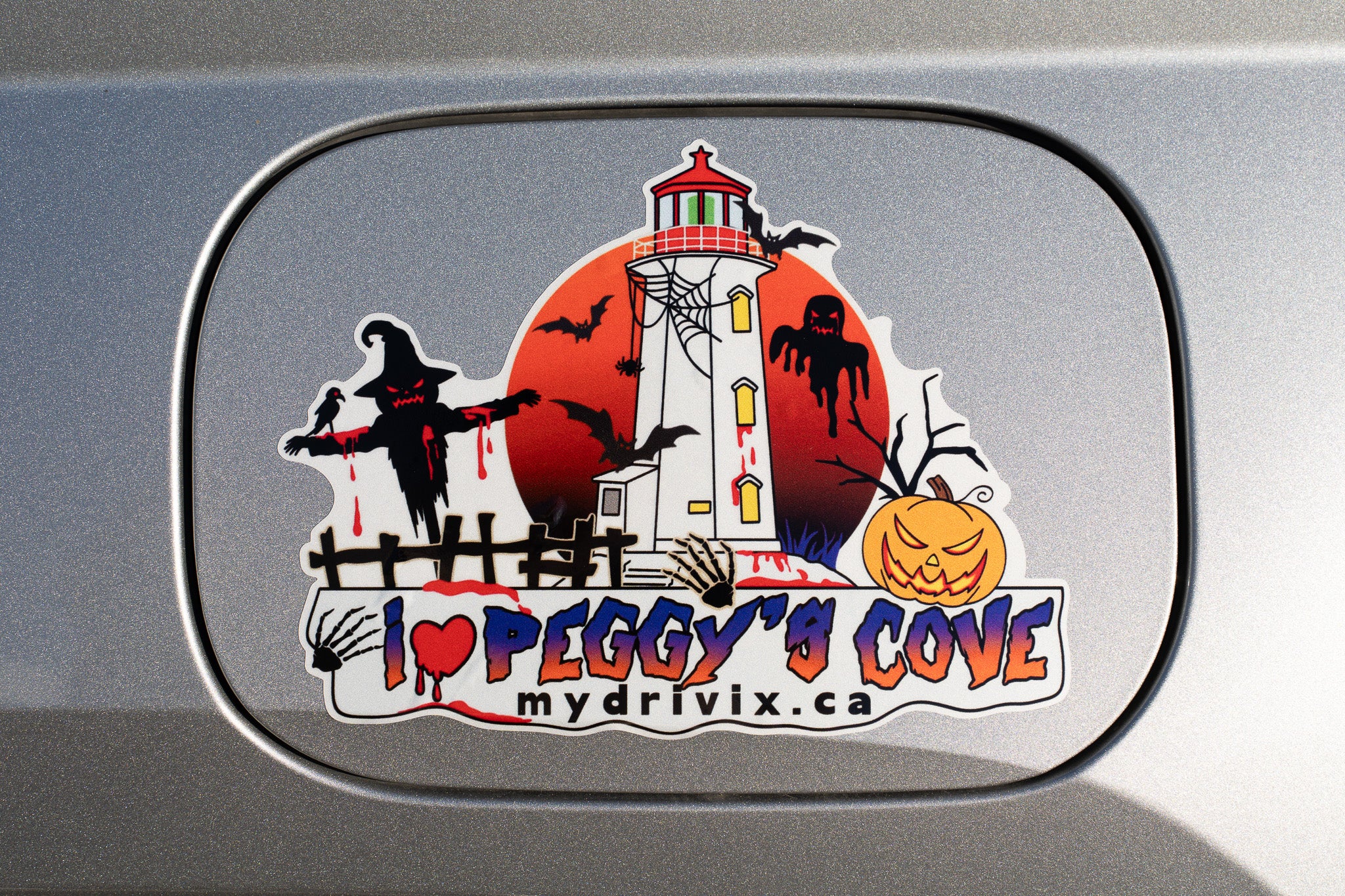 Halloween-themed sticker with a lighthouse and text on a car window