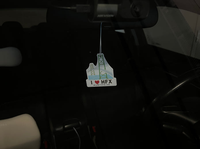 Air freshener with a lighthouse design hanging from a car's rearview mirror.