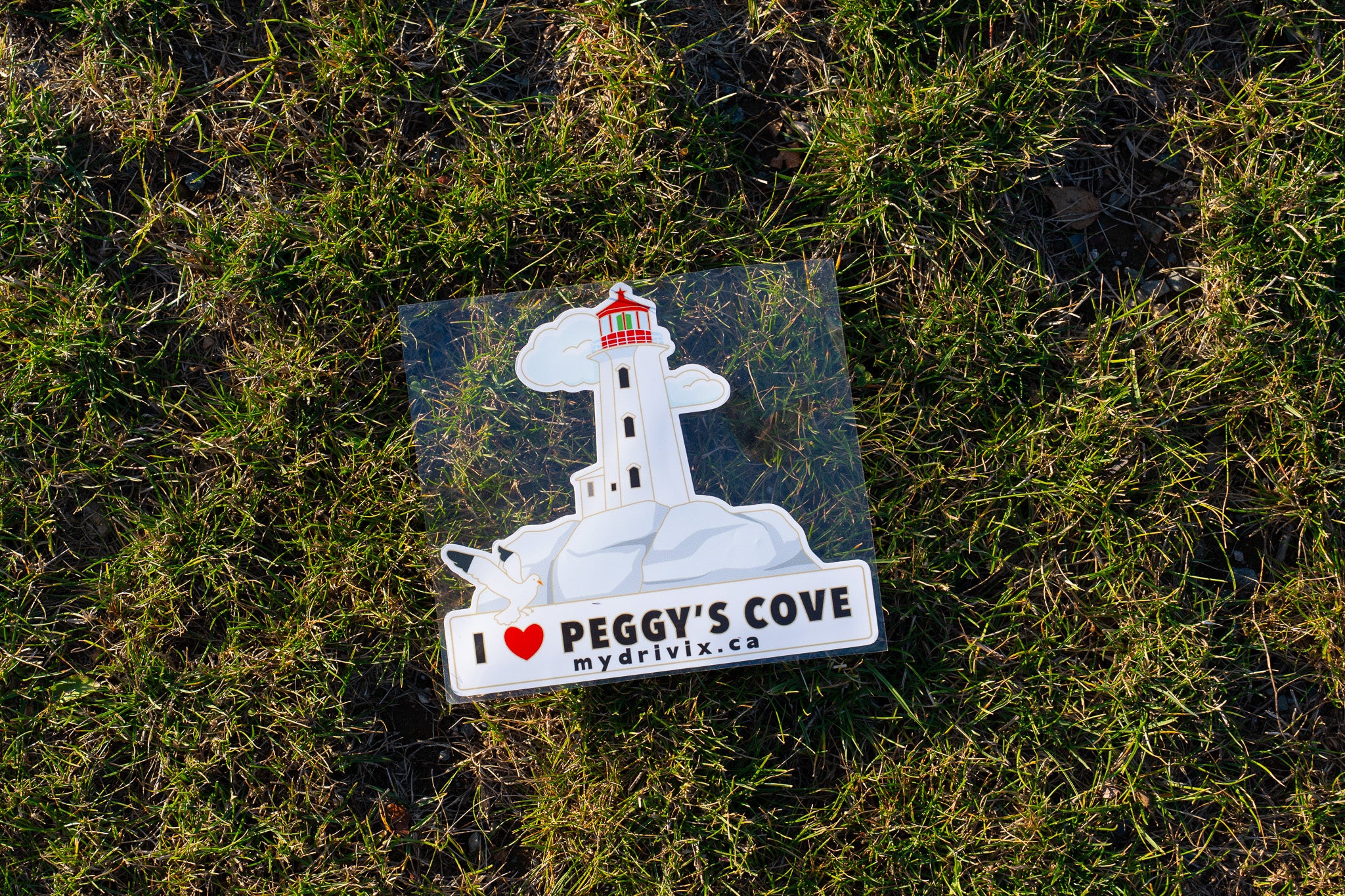 Sticker of a lighthouse with 'I ❤️ Peggy's Cove' text on grass