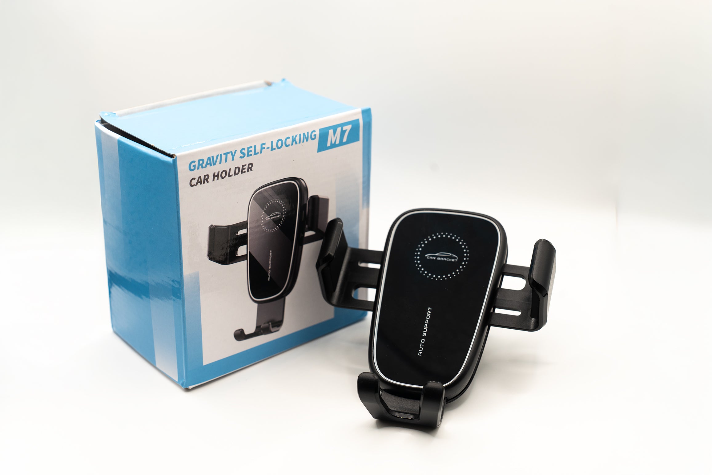 Black car holder with Gravity Self-Locking M7 branding next to its packaging on a white background