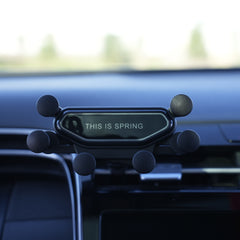 Phone holder on a car dashboard with 'This is Spring' text