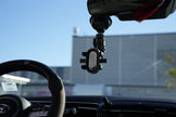 Phone holder attached to a car's rearview mirror with a blurred outdoor background