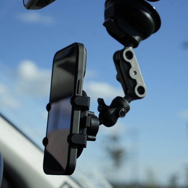 Phone mounted on a car dashboard with a clear blue sky background