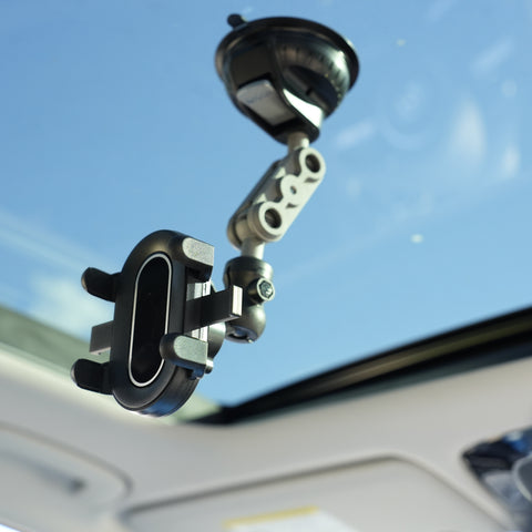 Car phone mount attached to a car's sun visor with a clear blue sky background.
