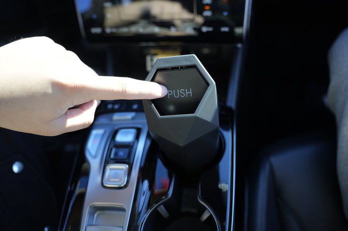 Hand pressing a button labeled 'PUSH' in a car interior.