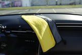 Yellow microfiber towel draped over a car's dashboard with a blurred background