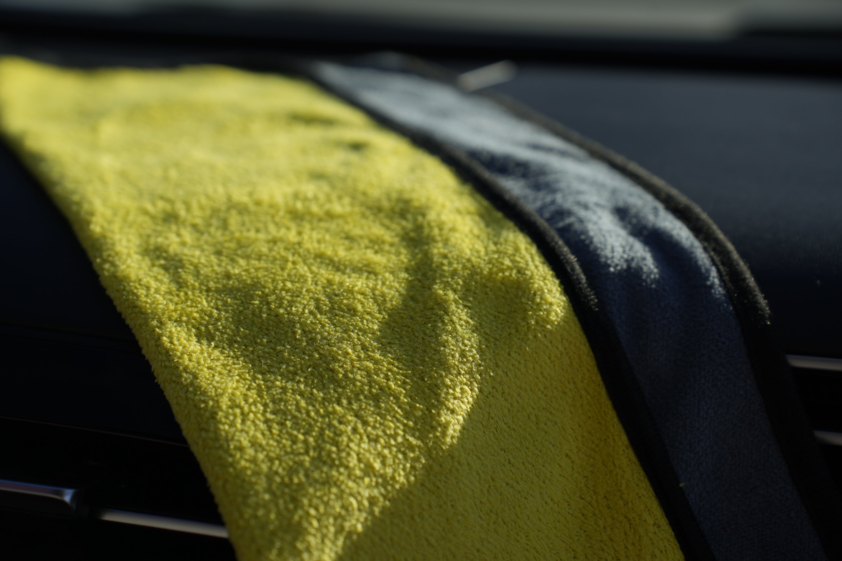 Close-up of a yellow microfiber towel draped over a car's air vent.
