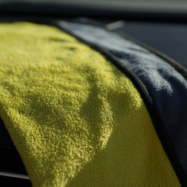Close-up of a yellow microfiber towel draped over a car's air vent.