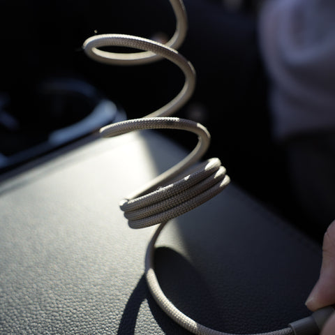 Coiled cable on a car dashboard with a hand holding it