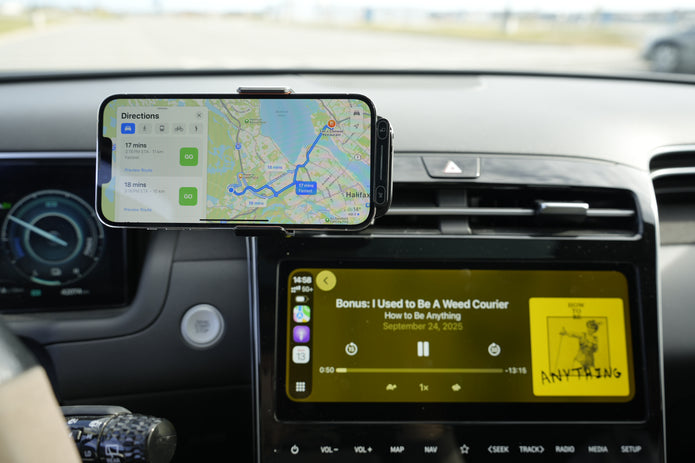 Phone mounted on a car dashboard displaying navigation and music app.