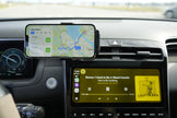 Phone mounted on a car dashboard displaying navigation and music app.