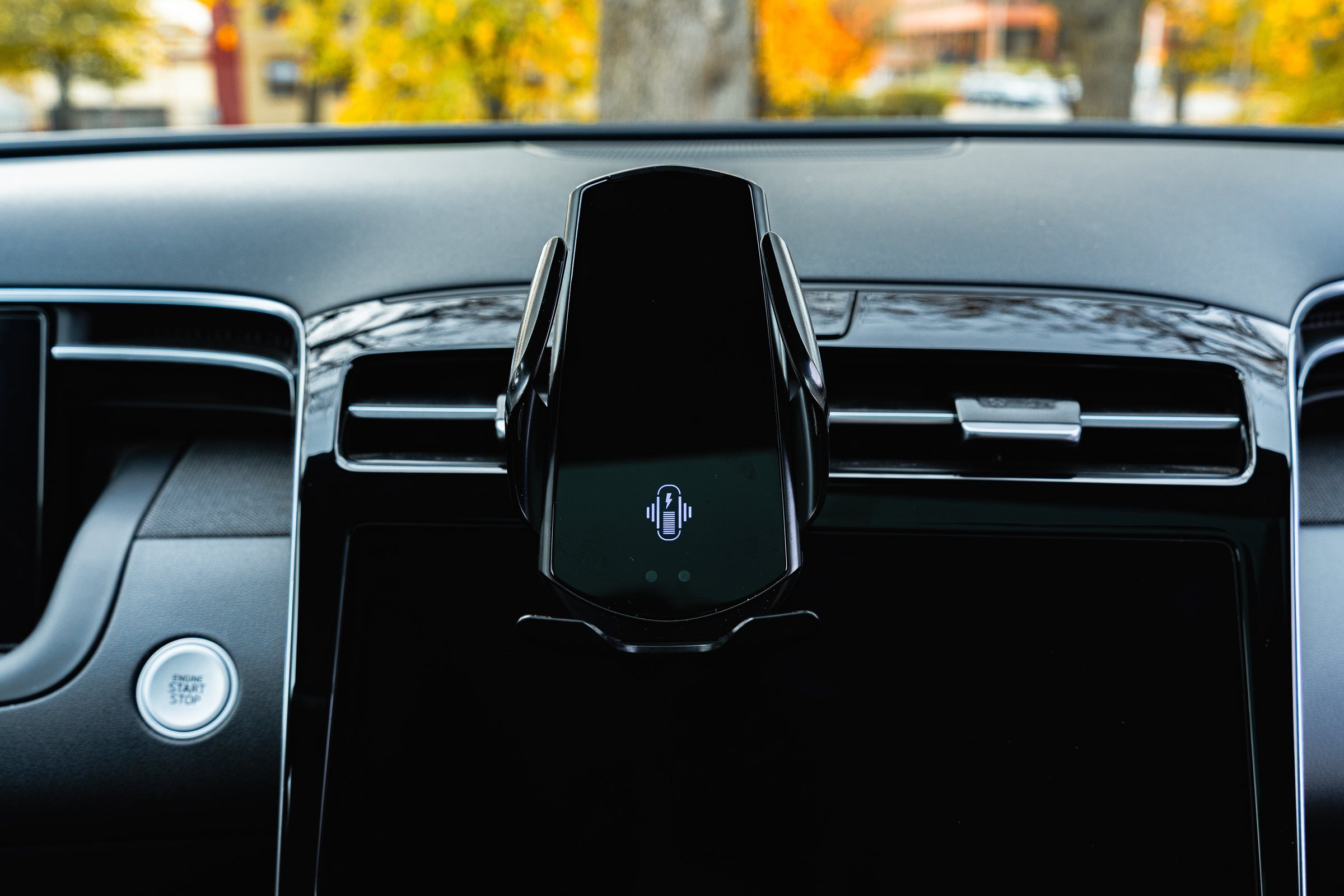 Car phone holder on a car dashboard with blurred outdoor background