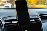Phone mounted on a car dashboard with a blurred outdoor background
