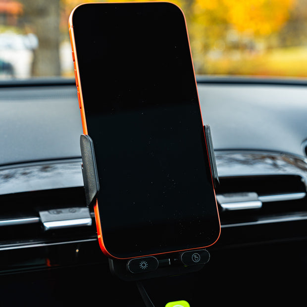 Phone mounted on a car dashboard with a blurred outdoor background