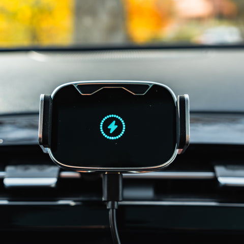 Wireless car charger on a car dashboard with a blurred outdoor background