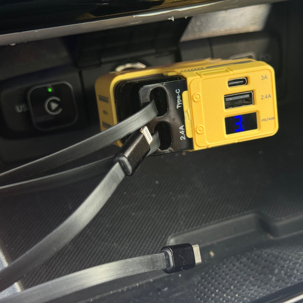 Yellow power adapter with USB ports and cable plugged into a car's USB port.